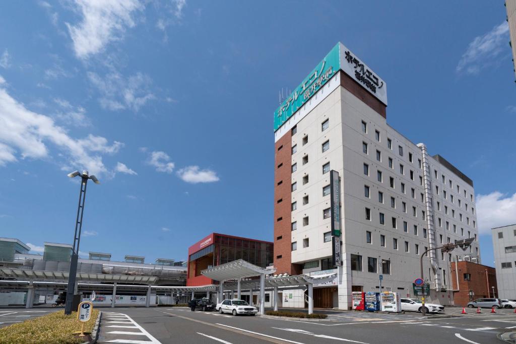 un edificio blanco alto en la esquina de una calle en Hotel Econo Fukui Station, en Fukui