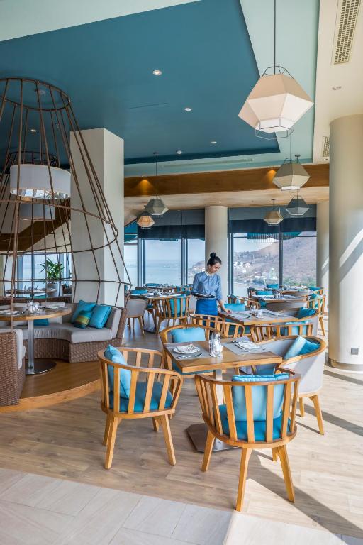 a restaurant with tables and chairs and a person in the background at Fusion Suites Vung Tau in Vung Tau