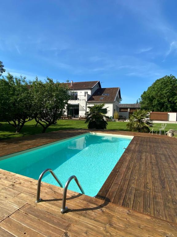 una piscina con terraza de madera y una casa en B&B La Laiterie de Fontpatour, en Vérines