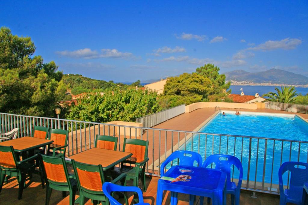 a balcony with tables and chairs and a swimming pool at Appartement charmant avec piscine à Porticcio - 32 m² in Porticcio