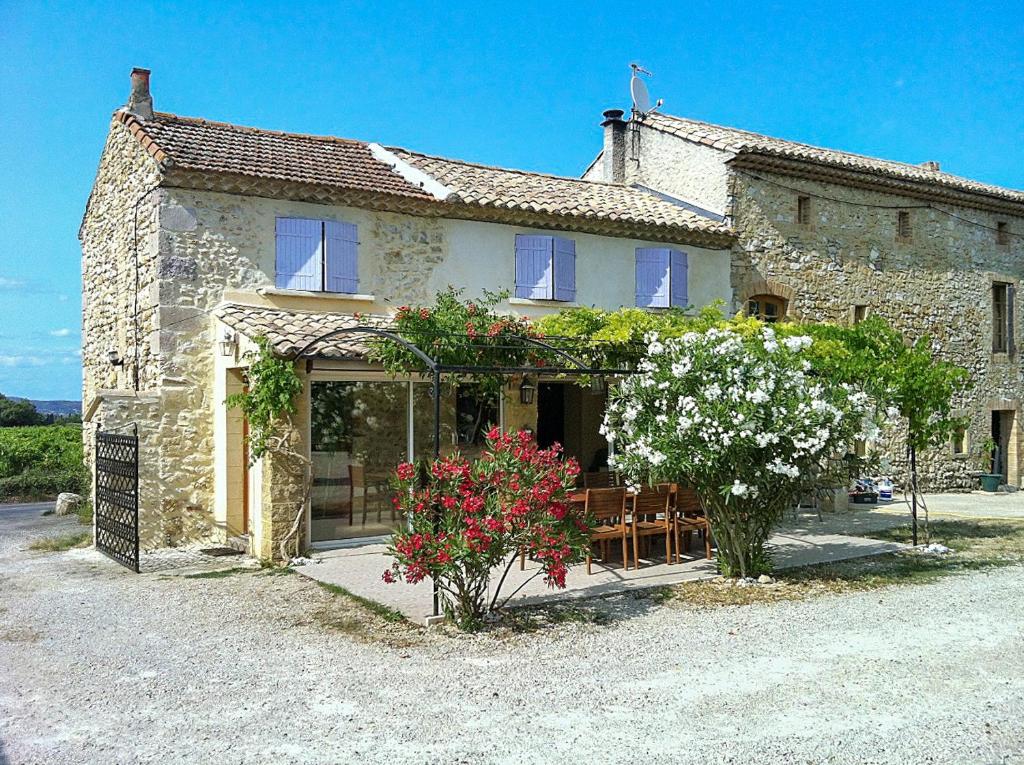 una casa de piedra con una mesa y flores delante de ella en Maison de 3 chambres avec piscine partagee jardin clos et wifi a Saint Victor la Coste, en Saint-Victor-la-Coste