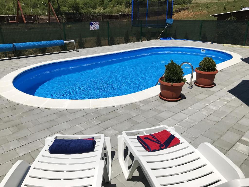 a pool with two lounge chairs and a table and avisorvisor at Charming Apartment in Rakovica with Shared Pool in Oštarski Stanovi