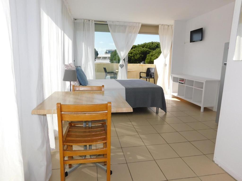 een slaapkamer met een bed, een tafel en stoelen bij studio 38 climatisé balcon vue mer in Le Grau-du-Roi