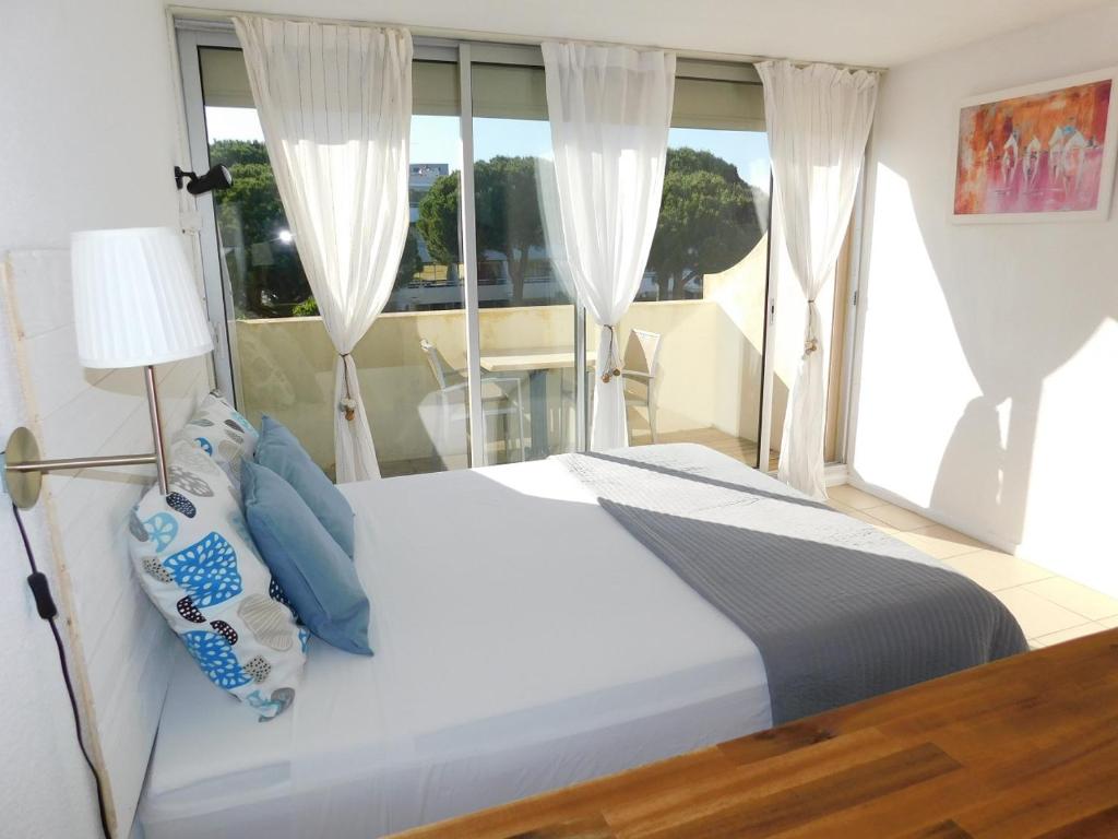 a bedroom with a white bed and a window at Studio 43 climatisé terrasse vue mer in Le Grau-du-Roi