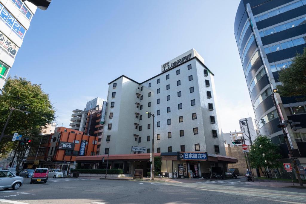 un edificio blanco alto en una calle de la ciudad en Hotel Econo Kanazawa Station, en Kanazawa