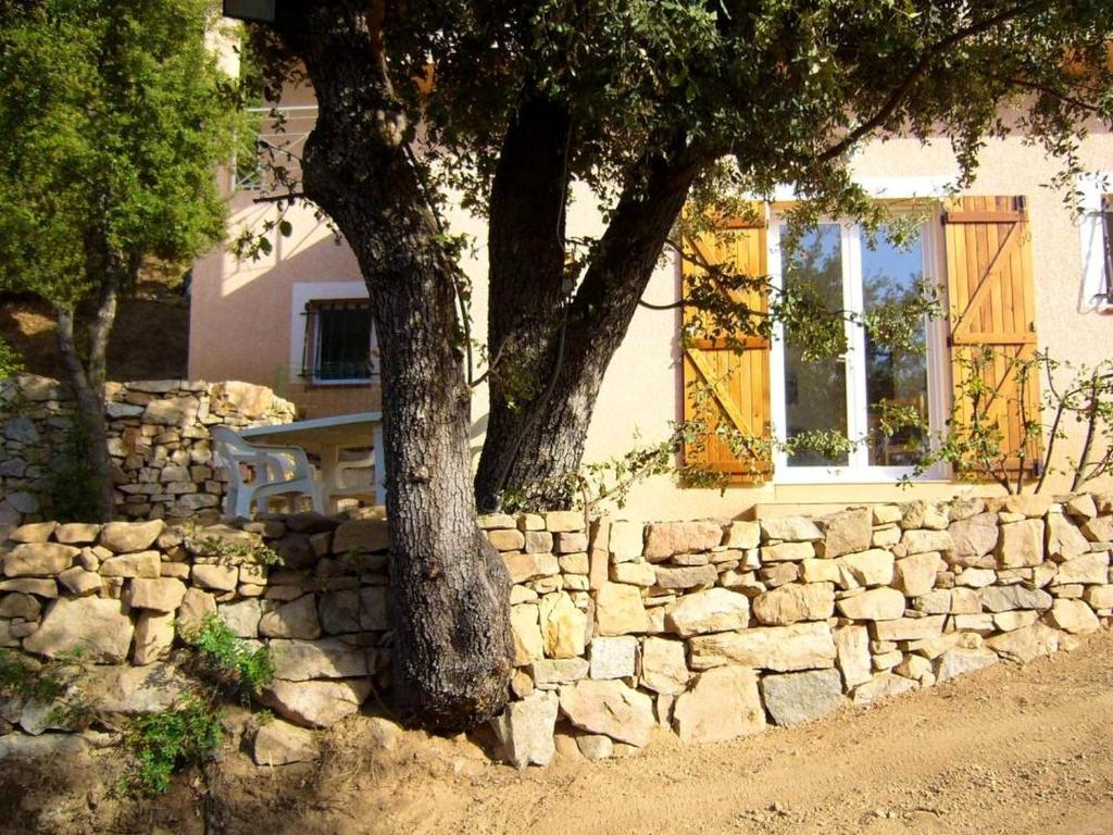 a stone wall with a tree in front of a building at Maison d'une chambre avec vue sur la mer jardin amenage et wifi a Alata a 8 km de la plage in Alata