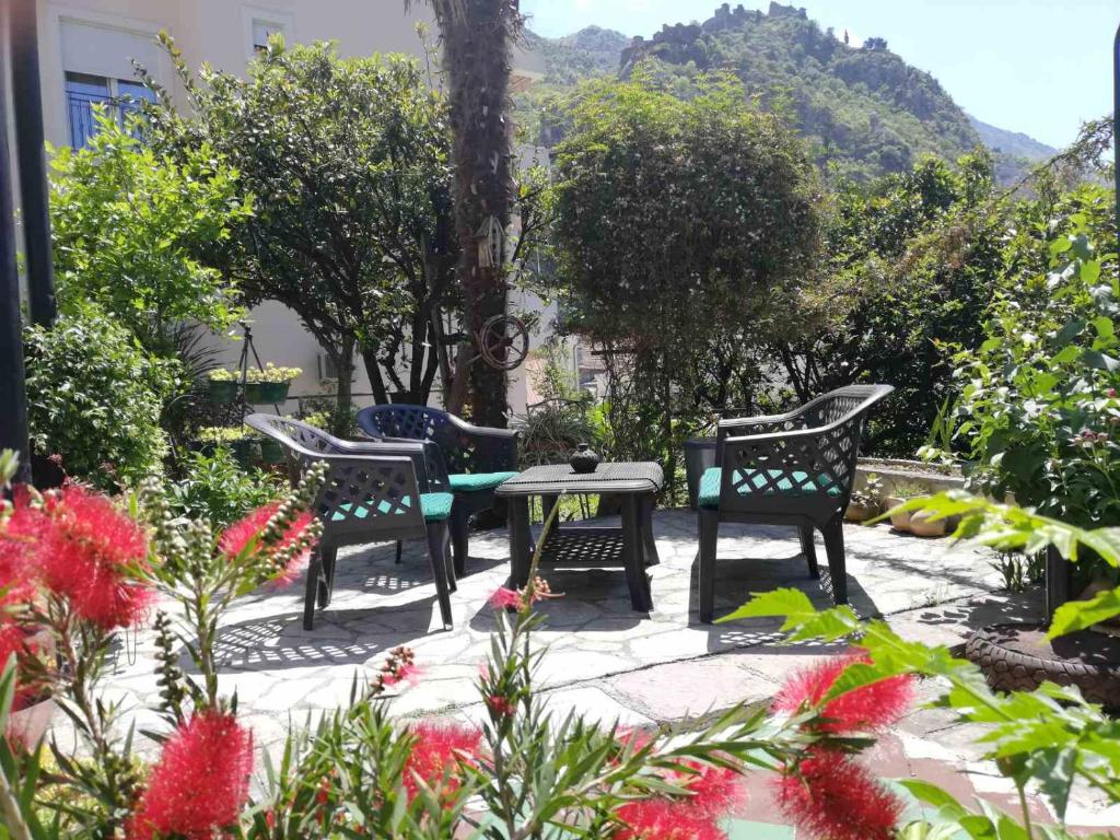 drie stoelen en een tafel in een tuin met bloemen bij Apartments Sandra in Kotor