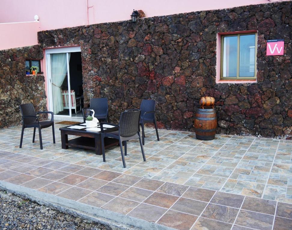 a patio with chairs and a table and a stone wall at APARTAMENTO LOS CACTUS in Echedo