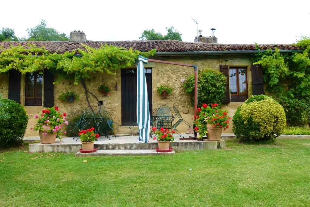 uma casa com flores e um guarda-chuva no quintal em Villa de 2 chambres avec piscine privee jardin clos et wifi a Ornezan em Ornézan