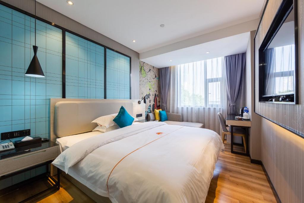 a bedroom with a large white bed with blue tiles at Warm Yes Business Hotel in Guangzhou