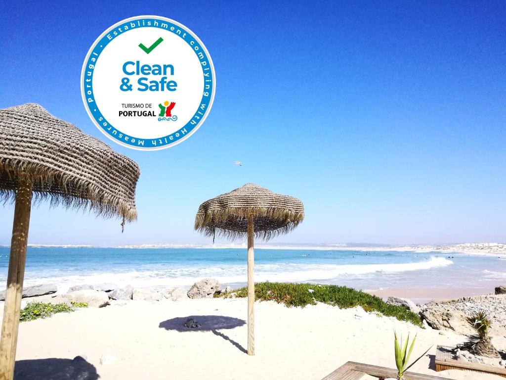 a sign for a clean and safe beach with umbrellas at Peniche's Blue & White in Peniche