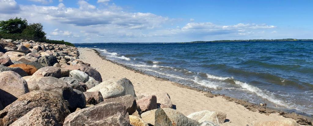 una playa con algunas rocas y el agua en Am Anker, en Langballig