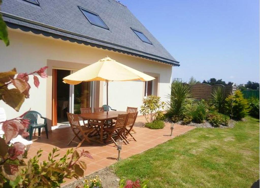 a patio with a table and an umbrella at Maison de 4 chambres a Plougrescant a 400 m de la plage avec vue sur la mer jardin clos et wifi in Plougrescant