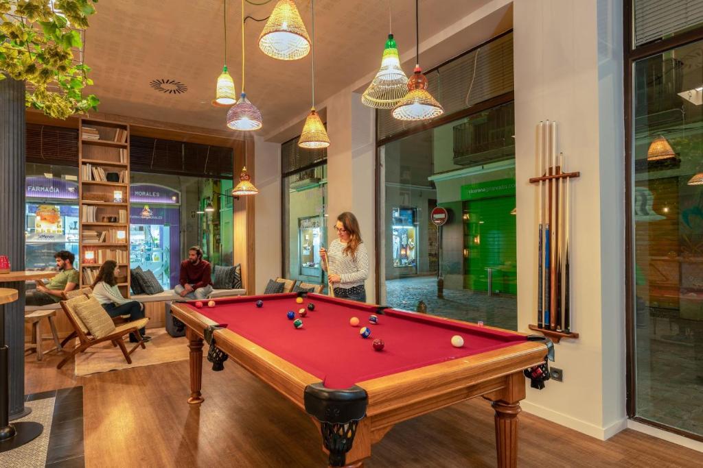 a pool table in a room with people sitting at Toc Hostel Granada in Granada