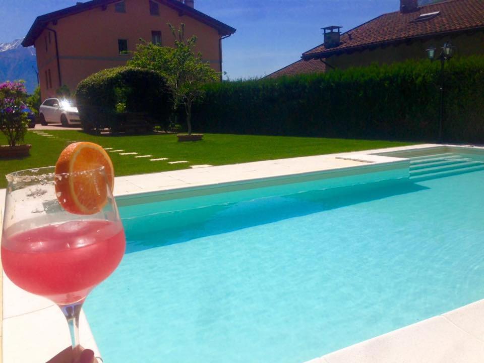 uma bebida com uma laranja num copo ao lado de uma piscina em Haus Barbara em Novate Mezzola
