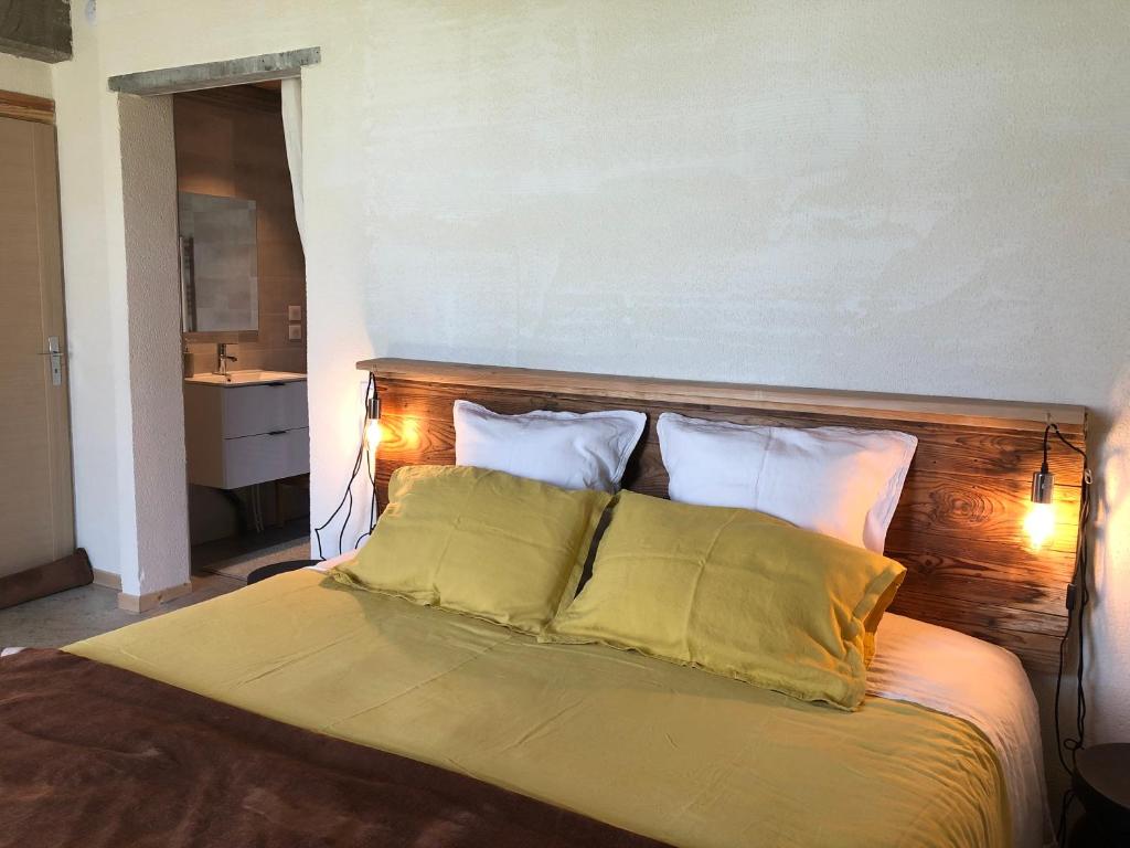 a bed with two pillows and a wooden head board at Coté Tiretaine in Orcines