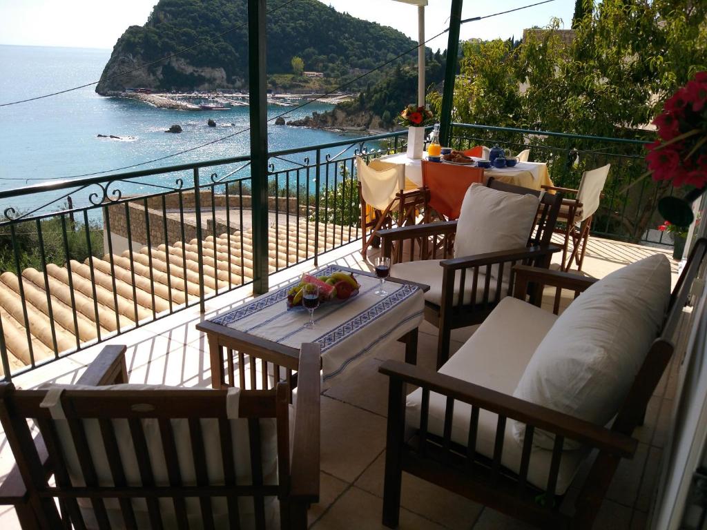uma varanda com cadeiras e uma mesa com vista para o oceano em Aliki Apartments em Paleokastritsa