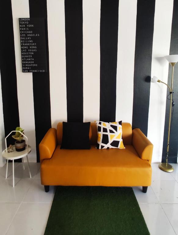 an orange couch in a room with a green rug at Nap at 265 Donmeaung in Bangkok