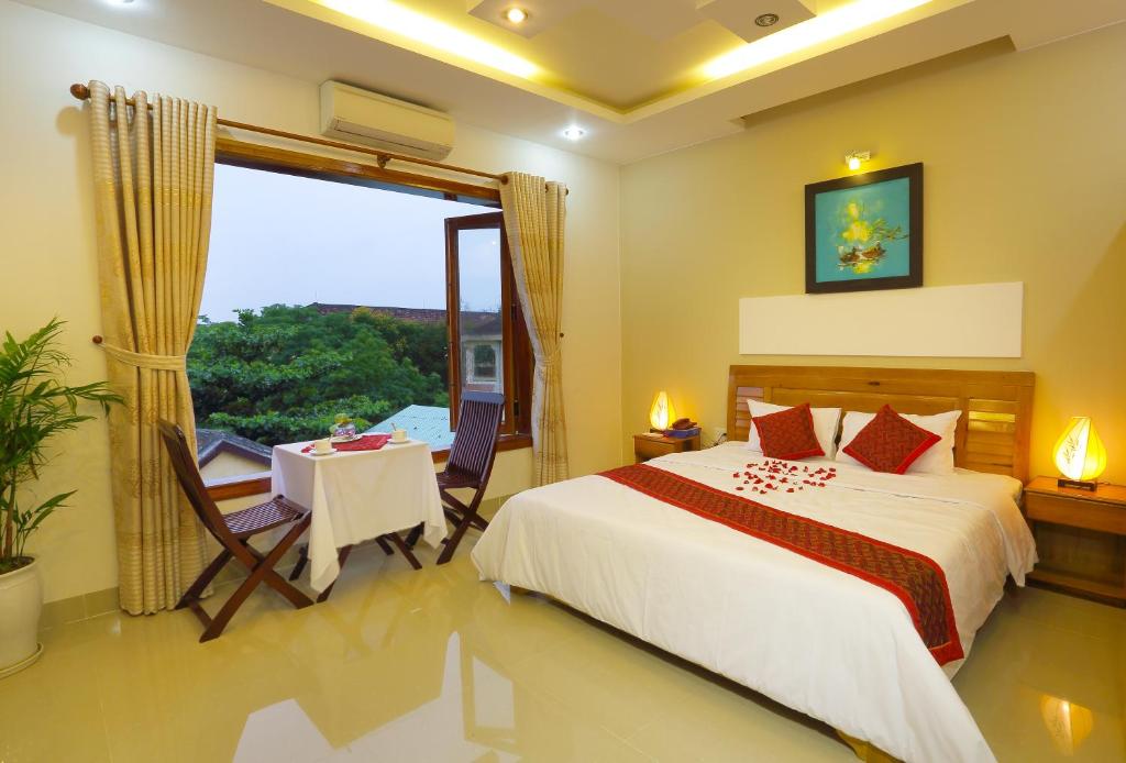 um quarto com uma cama, uma mesa e uma janela em Hoang Thu Hostel em Hoi An