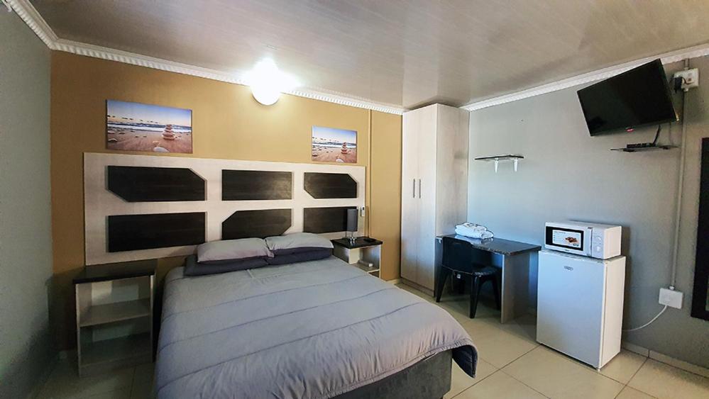 a bedroom with a bed and a desk and a television at Genesis Self Catering Apartments in Bloemfontein