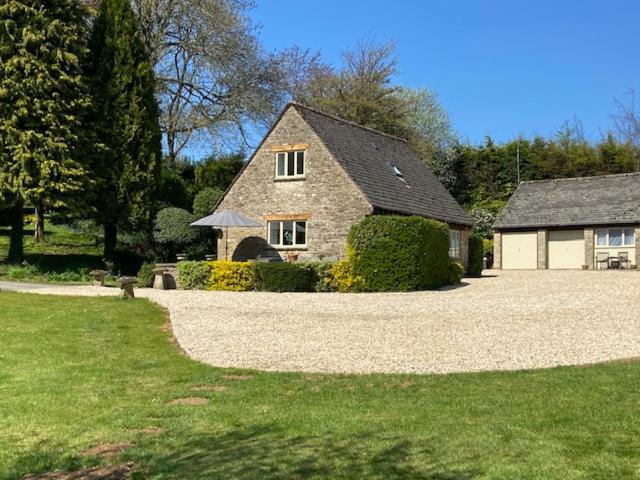 a stone house with a gravel driveway in a yard at Far Hill Cottage in Wyck Rissington