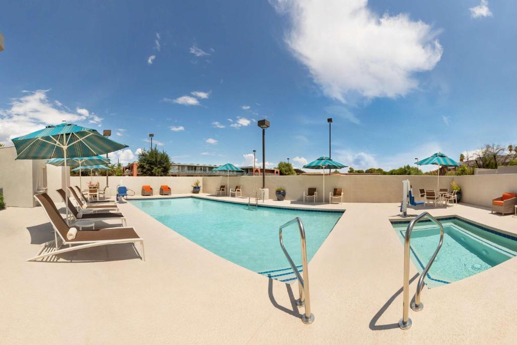 a swimming pool with lounge chairs and umbrellas at Hyatt Place Tucson Central in Tucson