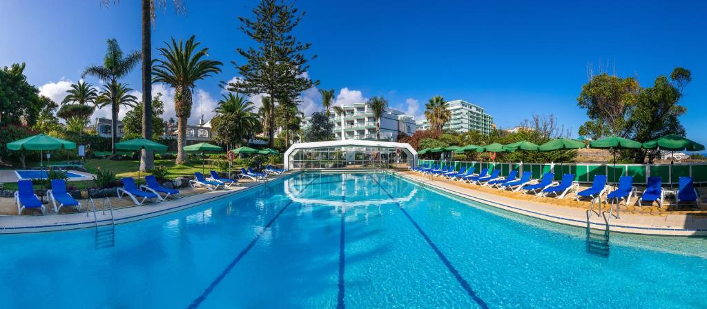 a large swimming pool with chairs and umbrellas at Parque Vacacional Eden in Puerto de la Cruz