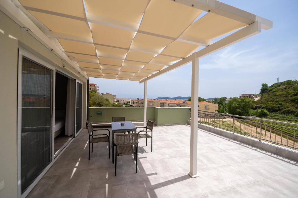 a patio with a table and chairs on a balcony at Lofos Apartments in Nea Peramos