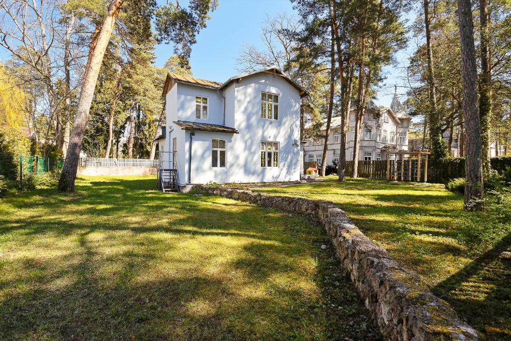 a white house in the middle of a yard at Holiday Home Viktorija B in Jūrmala