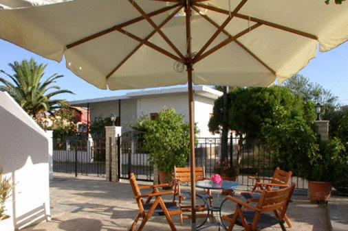 a patio with a table and chairs under an umbrella at Studios Akrogiali in Kyparissia