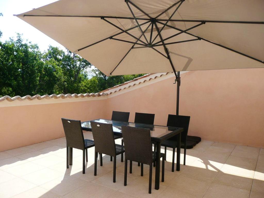 une table et des chaises avec un parasol sur une terrasse dans l'établissement Appartement charmant à Sainte Croix du Verdon avec terrasse, à Sainte-Croix-de-Verdon