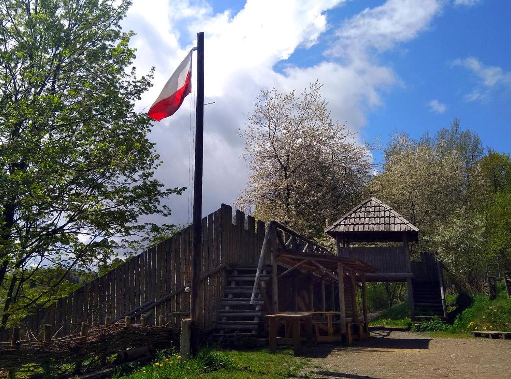 una bandera en un poste junto a una valla de madera en Baza biwakowa "Warownia", en Srebrna Góra