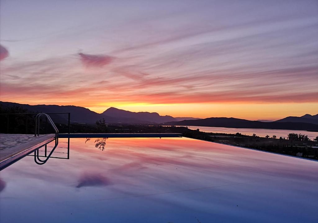 ガラタスにあるSaronic TopView Villaの夕日を背景に見えるスイミングプール