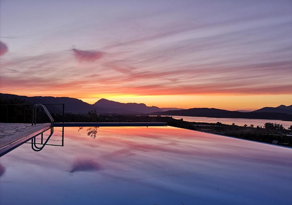 a swimming pool with a sunset in the background at Saronic TopView Villa in Galatas