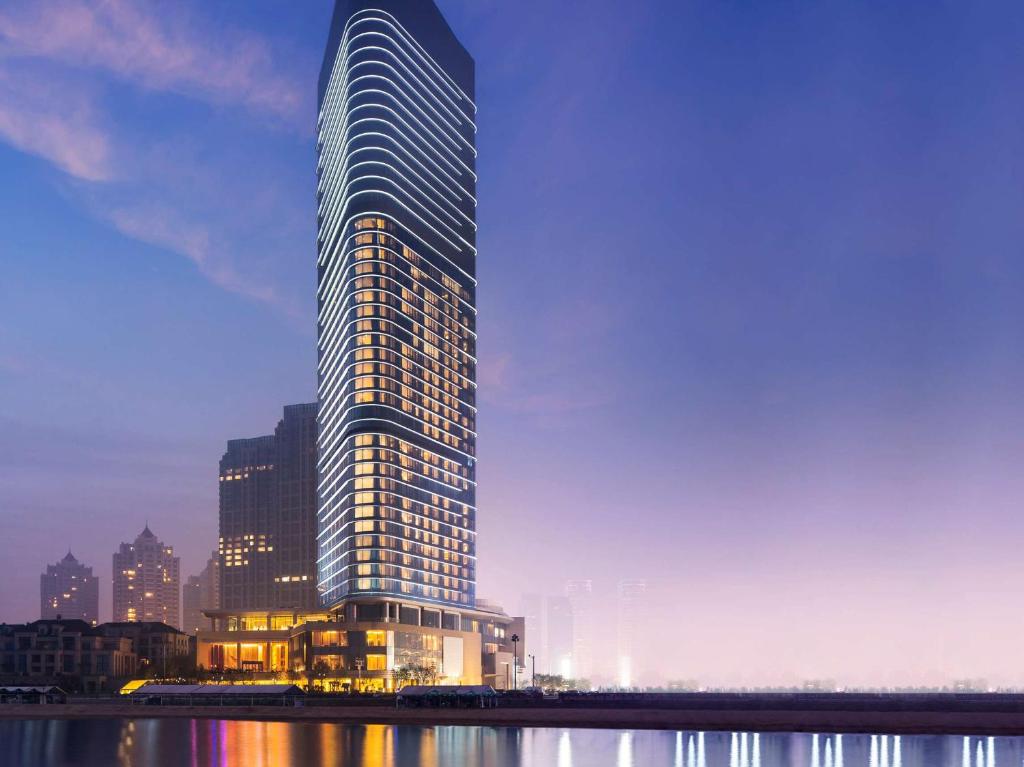 un edificio alto junto a un cuerpo de agua en Grand Hyatt Dalian en Dalian