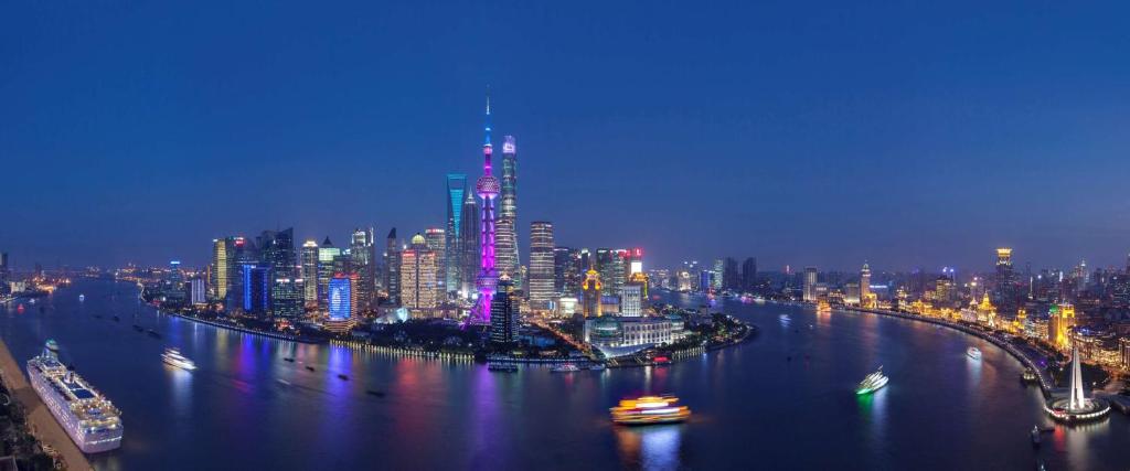 a city skyline at night with a river with boats at Hyatt on the Bund in Shanghai