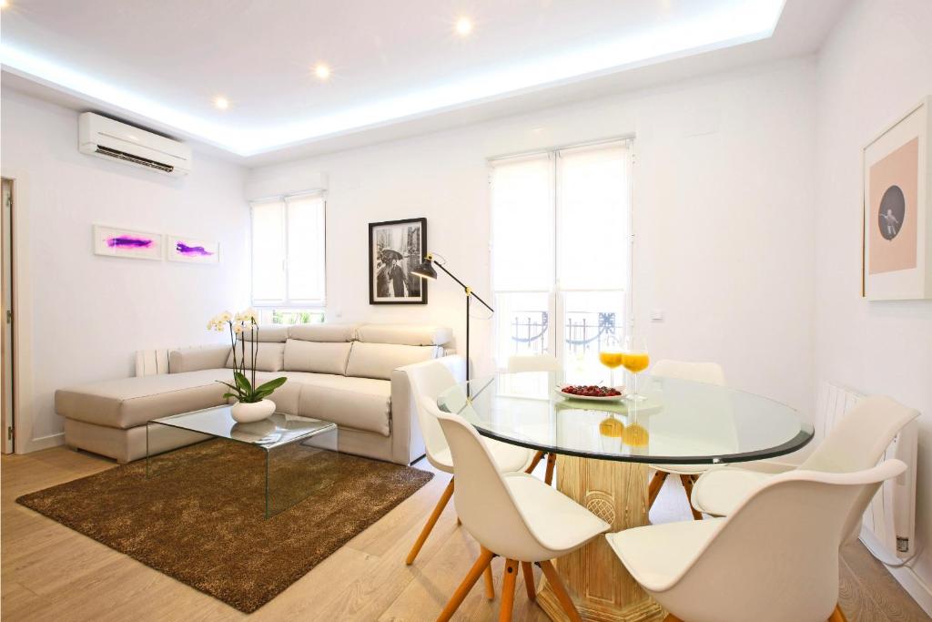 a white living room with a glass table and white chairs at Sofía by Madflats Collection in Madrid