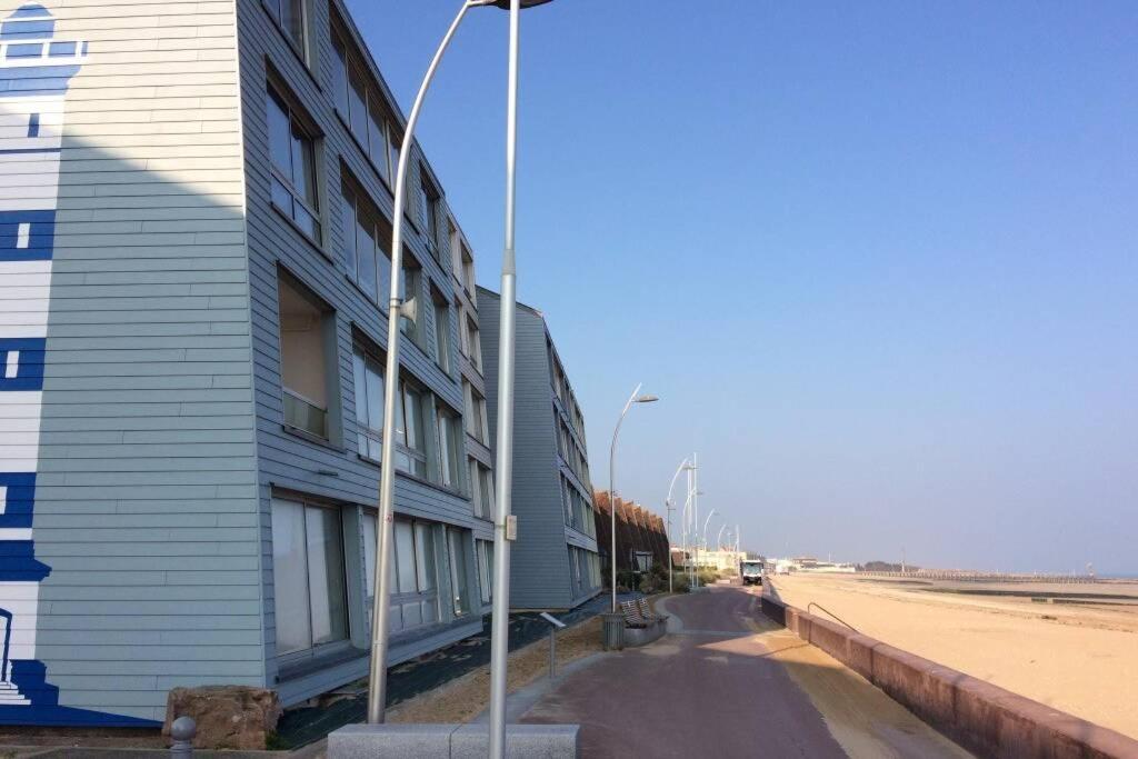 ein Gebäude an der Seite einer Straße neben einem Strand in der Unterkunft Appartement T2 avec vue sur mer directe ! in Courseulles-sur-Mer