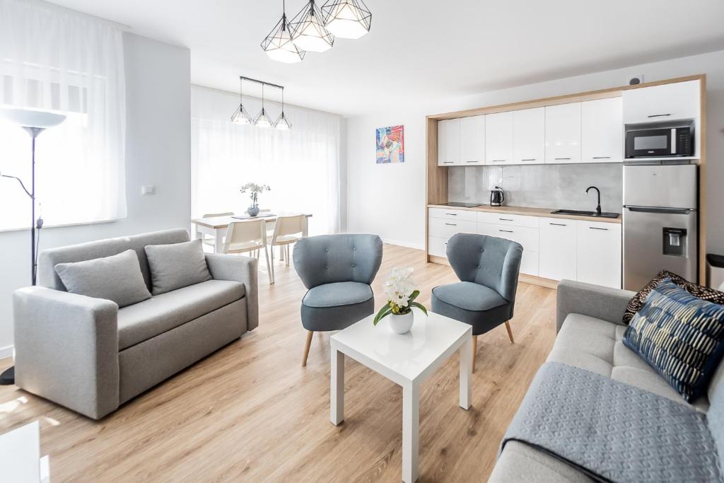 a living room with a couch and chairs and a kitchen at Apartament Margo in Łeba