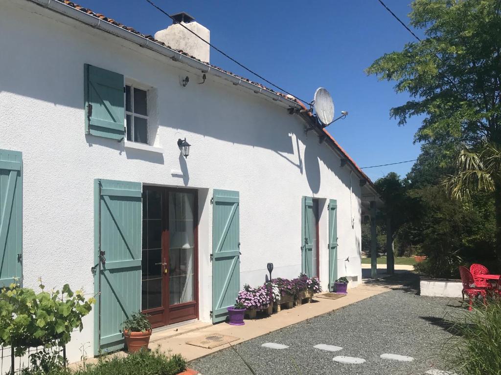 a white house with green shutters and flowers in front of it at La Blatière French Cottages in La Chapelle-Saint-Étienne