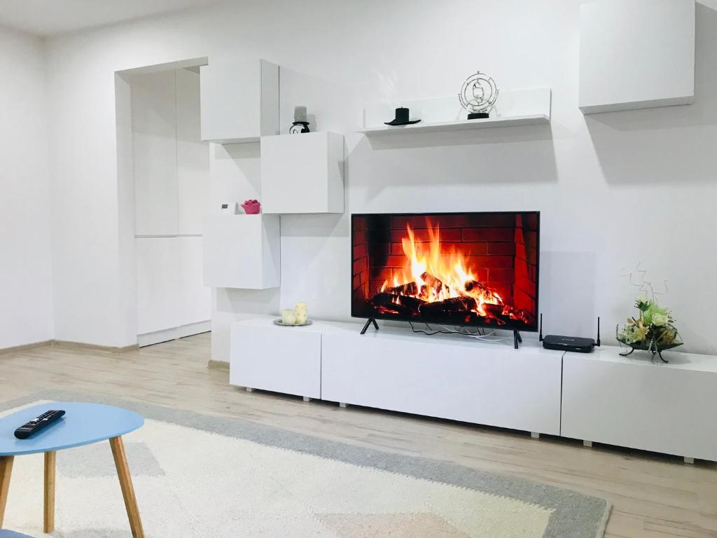 a fireplace in a white living room with a fire at Comfy apartment in Carei