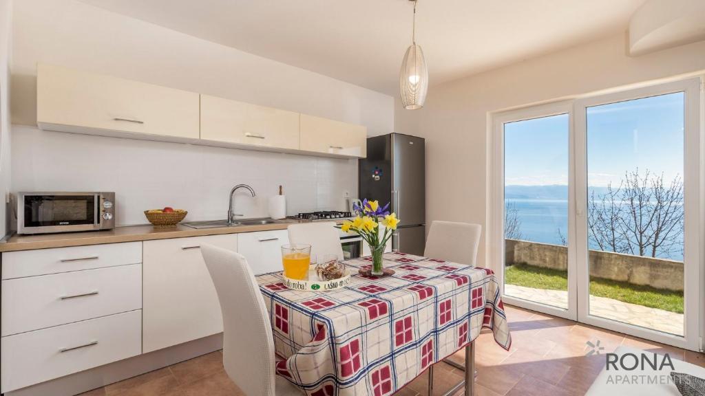 a kitchen with a table with chairs and a window at Rona Apartment Vintage Marin and Cute Lara in Lovran