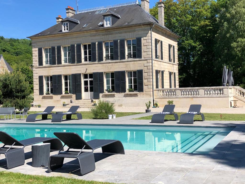 une maison avec une piscine et des chaises en face de celle-ci dans l'établissement Le Baptistère - Adults only, à Attichy