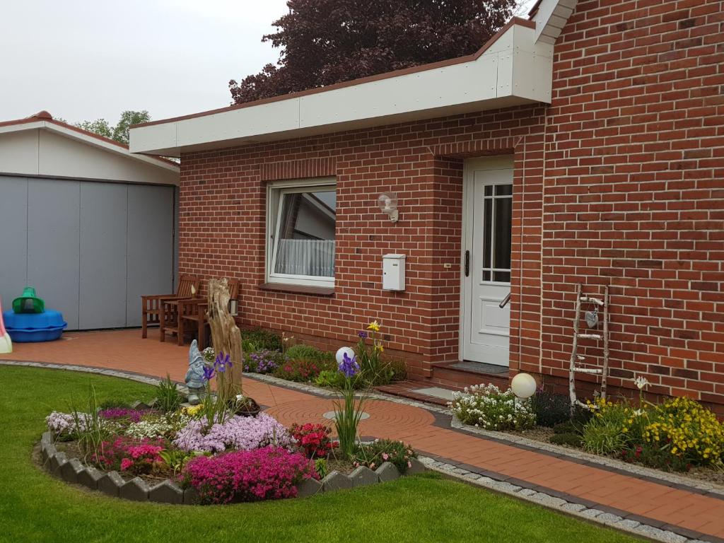 a brick house with a flower garden in front of it at Ferienwohnung beim Bracksee in Wischhafen