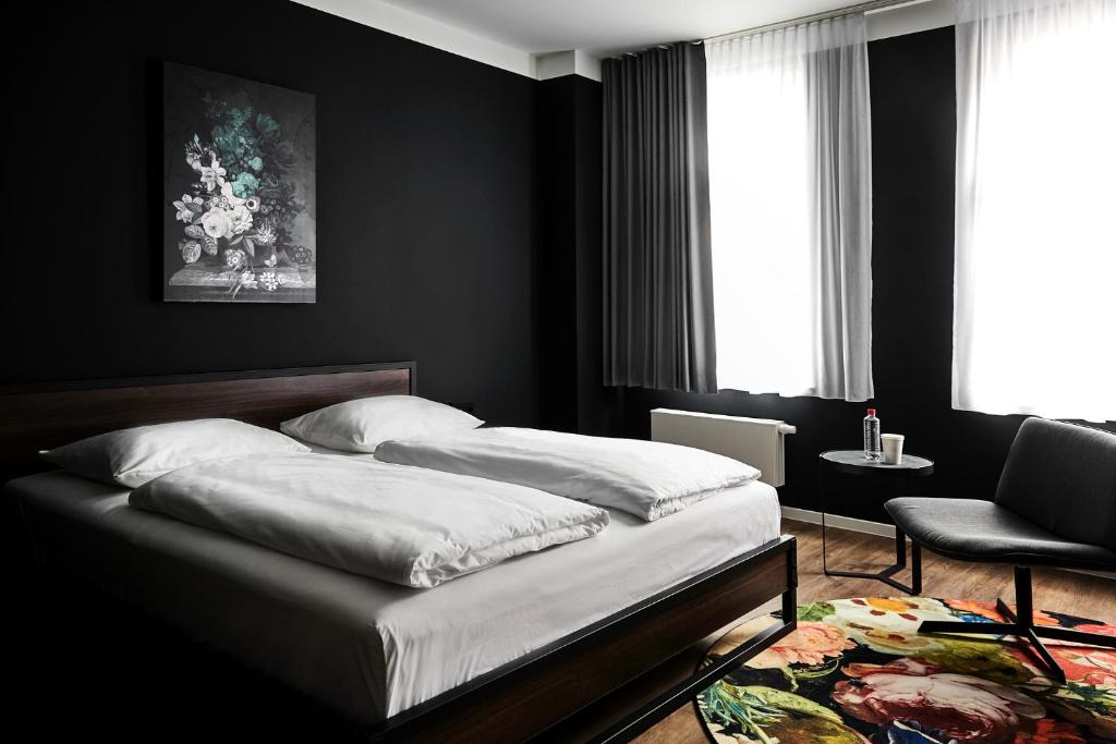 a black bedroom with a bed and a chair at GRONERS Leipzig in Leipzig