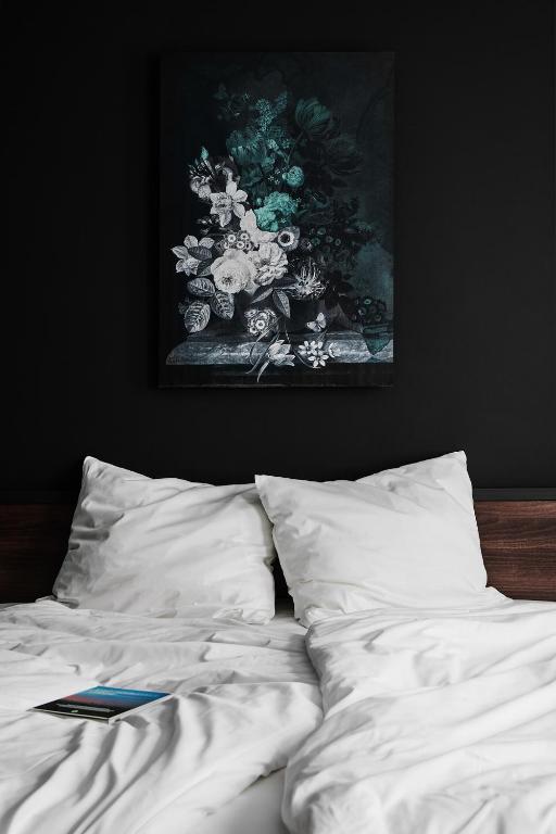 a bed with white sheets and a picture on the wall at GRONERS Leipzig City Center in Leipzig
