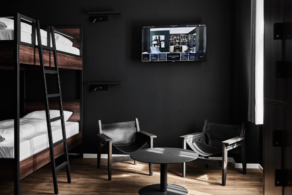 a room with two bunk beds and two chairs and a table at GRONERS Leipzig City Center in Leipzig