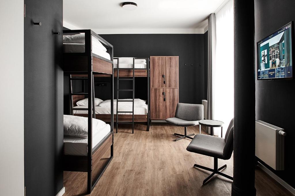 a dorm room with bunk beds and a desk and chair at GRONERS Leipzig City Center in Leipzig