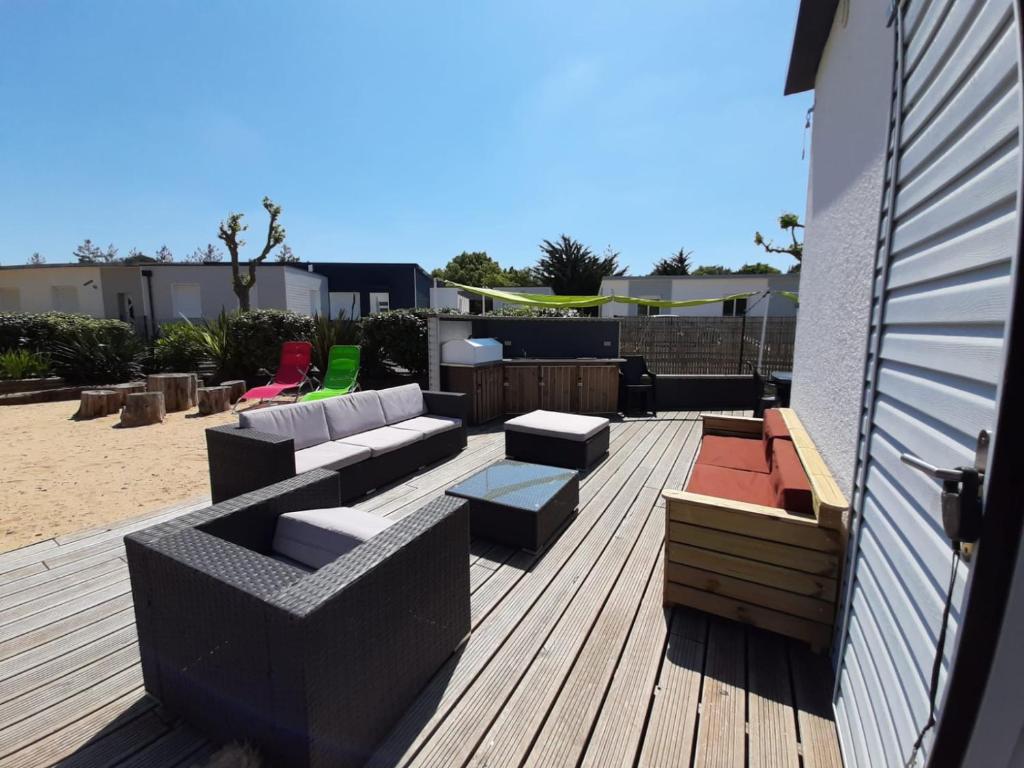 un patio con sofá y sillas en una terraza de madera en CLOS DE L'OCEAN 2 - maison 3 chambres à 300 m de la plage en Saint-Jean-de-Monts