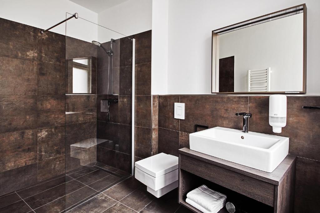 a bathroom with a sink and a toilet and a mirror at GRONERS Leipzig City Center in Leipzig